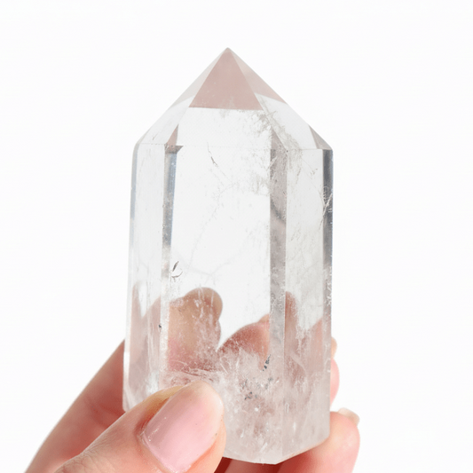 Clear crystal held in a hand against a white background