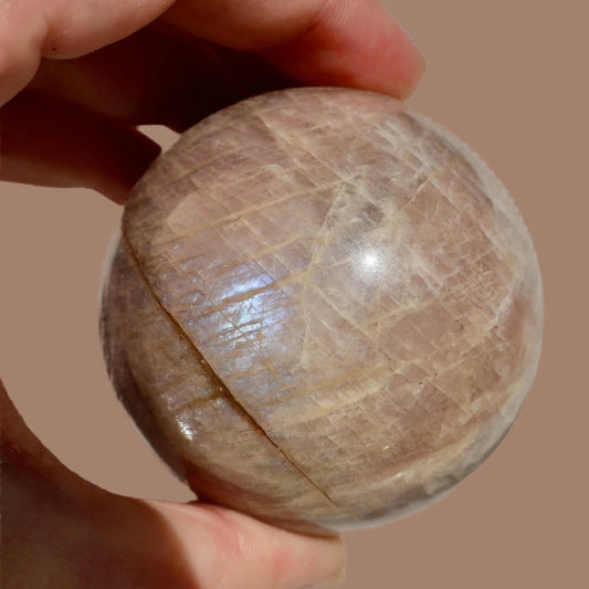 Natural moonstone crystal sphere displaying prismatic adularescence and blue-white glow for crystal collectors