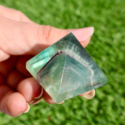 green and purple fluorite pyramids on grass, 1-inch crystal cut