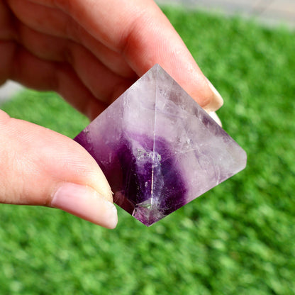 green and purple fluorite pyramids on grass, 1-inch crystal cut