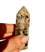 Hand-polished moonstone obelisk displaying natural adularescence and silvery-blue iridescent flash against neutral background