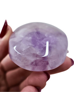 Hand holding a purple crystal against a white background