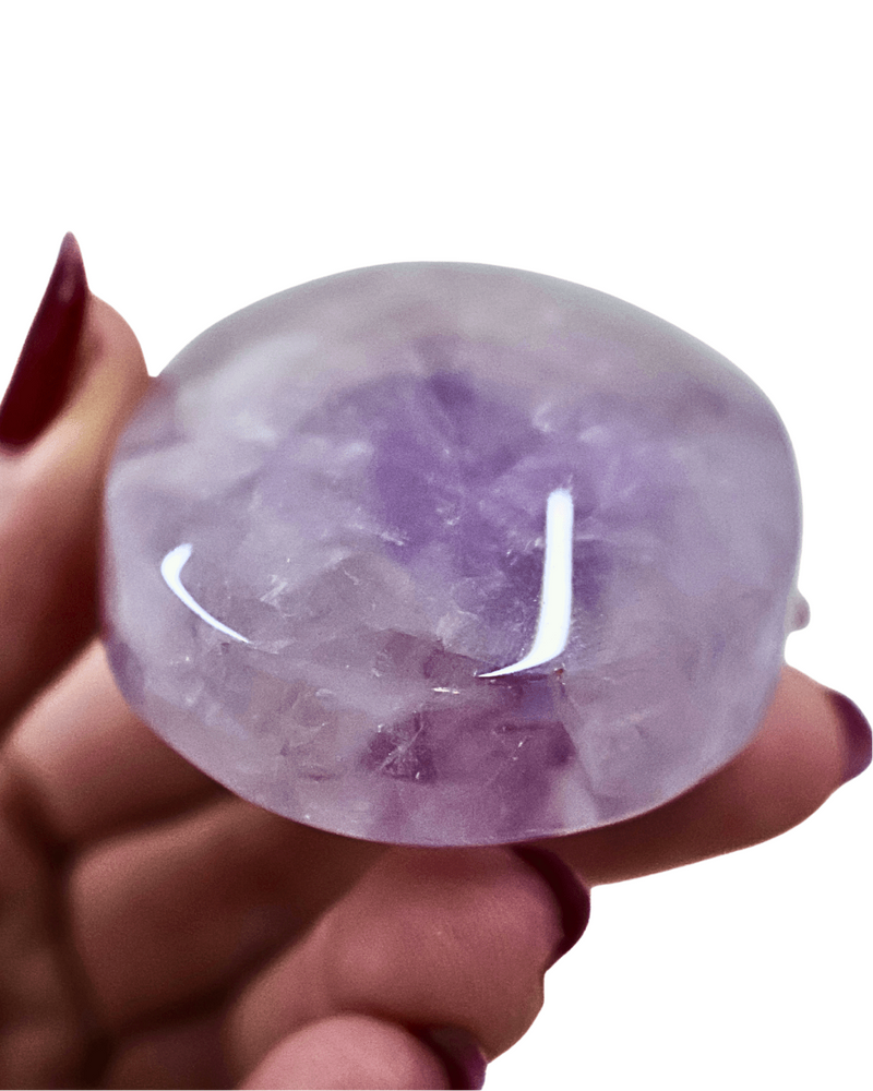 Hand holding a purple crystal against a white background